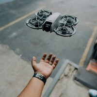 A drone hovers above a person's outstretched hand by Laurent Yasiel