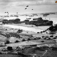 Landing ships putting cargo ashore on Omaha Beach, at low tide
