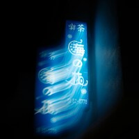 A blurry blue neon sign with japanese characters in darkness by jack berry