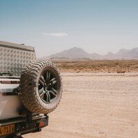 Off-road vehicle parked in a dry, dusty desert landscape by NIR HIMI
