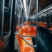 Empty orange plastic seats inside a brightly lit subway car by Dongsh