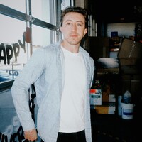 Man in casual clothing standing near a garage door by LOGAN WEAVER | @LGNWVR