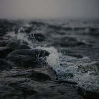 Waves crashing on rocky shore under a foggy sky by Kristaps Solims