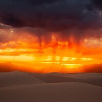 Dramatic sunset over sand dunes with rain falling by Colin Lloyd