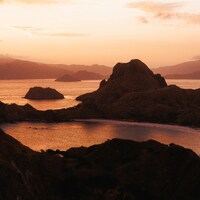Hills and ocean at sunset with warm light by Antonin Fontaine