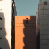 Tall buildings with strong shadows under a clear blue sky by Alexander Kaufmann