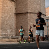 Three men running a race past a stone building by charlie dt