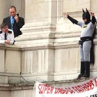 A police officer, left, watches a protester dressed as Batman