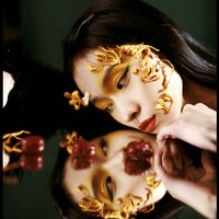 Woman with artistic makeup and floral accents reflected by Justin Chien