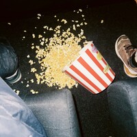 Spilled popcorn bucket on a dark movie theater floor by Andrew Solok 🇺🇦