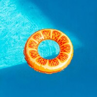 Orange slice inflatable float in a blue swimming pool by Andrew A
