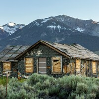 An old abandoned house stands before snow-capped mountains by Leo_Visions