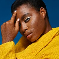 Woman with white eyeliner and yellow jacket by marcus pobee