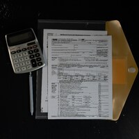 Calculator and papers in a folder on a dark surface by Kelly Sikkema