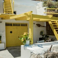 White building with yellow stairs and colorful awnings, milos by Anastase Maragos