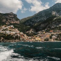 Coastal town nestled into steep mountains with ocean in foreground by Ahmet Yüksek ✪