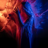 Figure shrouded in translucent fabric with red and blue lights by Sofia Lasheva
