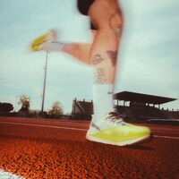Runner's legs in motion on a track by Kenny Leys