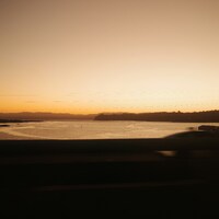 Sunset over a calm body of water by Archee Lal