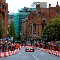 Jenson Button drives a McLaren through the streets of Manchester in a McLaren