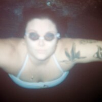 Woman swimming underwater in goggles with arm tattoos by Brooke Balentine