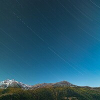 Star trails over mountains at night by Ryan Klaus