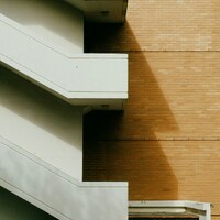 White staircase against a brick building with shadow by Nguyen Minh